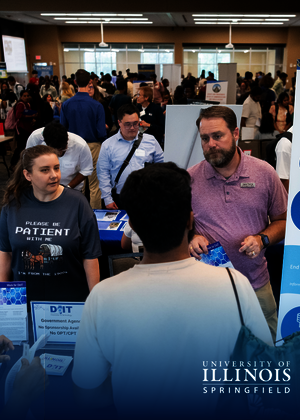 People engaging at a university career fair booth.