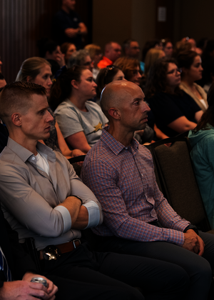 Audience attentively listening in a dimly lit conference room.