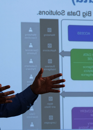 Man giving a presentation with a slide in the background.