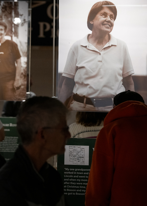 Exhibition with large portraits of people, dark silhouettes in foreground.