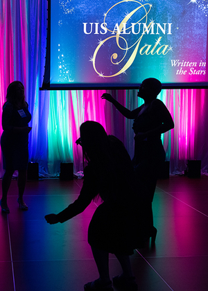 Silhouetted dancers at a colorful gala event.