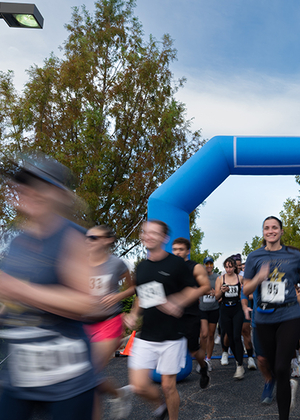 Runners passing a blue inflatable arch, blurred motion.
