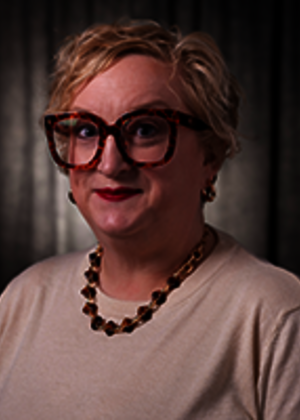 Sarah Adams smiling at the camera with a grey background.