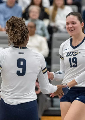 UIS volleyball players engaging on court between points