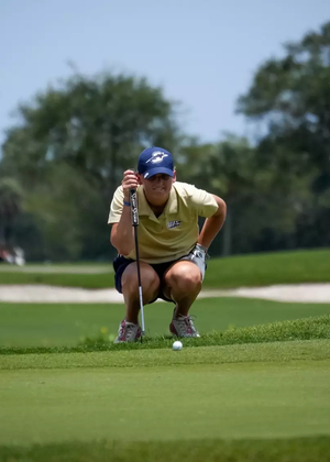 Elaine Grant in gold UIS polo and blue UIS hat golfing