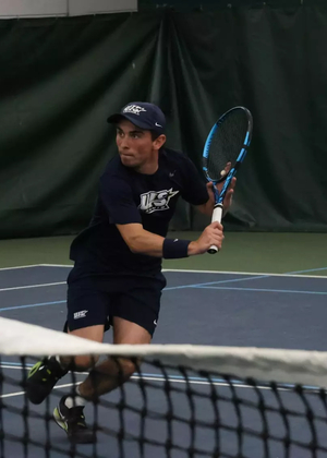 Pablo Herrera playing tennis in UIS blue in indoor facility