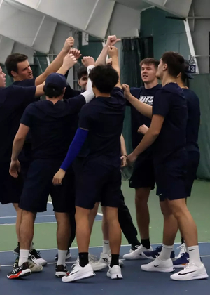 UIS men's tennis team in a huddle at indoor facility