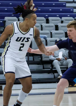 Jordan Rice playing basketball in white UIS uniform
