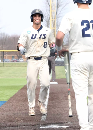 Noah Caceres celebrates hitting a home run in white UIS baseball uniform