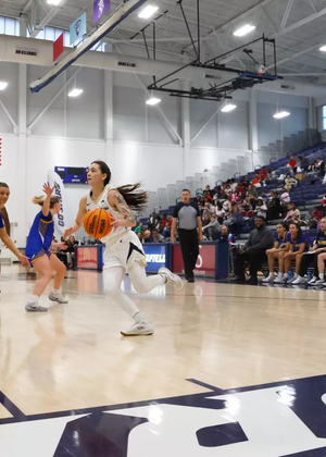 Kennedy Osterman playing basketball in front of home crowd