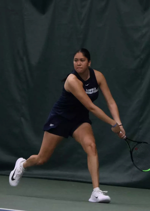 Cristina Mendoza Romero playing tennis in blue UIS uniform