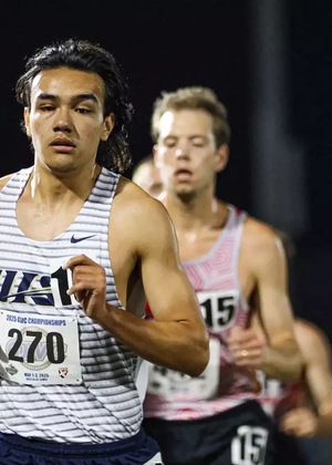 Matt Padilla running outdoor track in white UIS jersey
