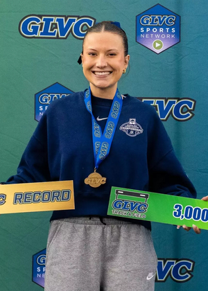 Madelyn Miller Ross poses in front of GLVC branded signage with All-GLVC medal and sign