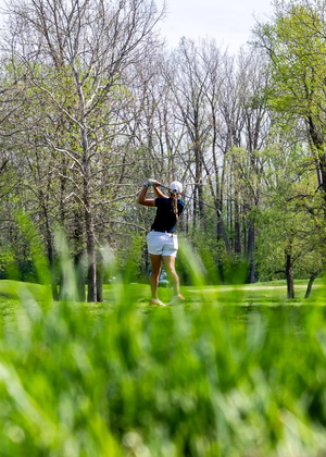 Elaine Grant golfing from afar, she is pictured in blue polo and white bottoms at GLVC Golf Tournament
