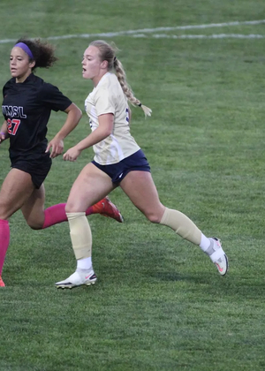 Carolyne Mathenia running on the pitch with an opponent