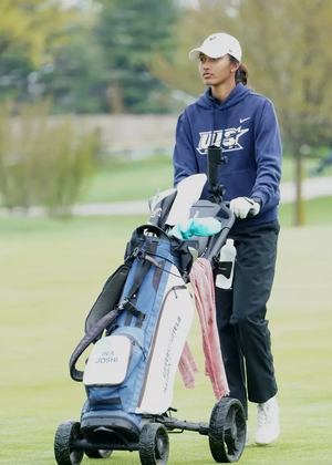 Ira Joshi pushing bag cart on golf course