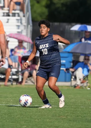 Ellie Mejia playing soccer in blue UIS uniform