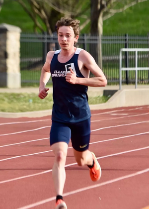 Garrett Wagoner running outdoor track in blue UIS uniform