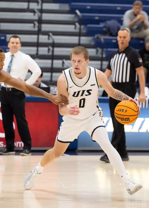 Britton Dutton playing basketball in white UIS uniform