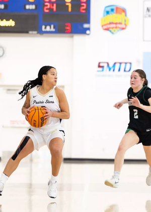 Kayla Rice playing basketball in white UIS uniform