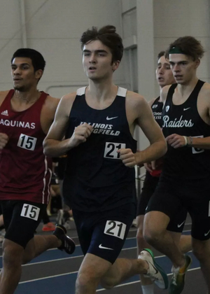 Owen Whelan running indoor track in blue UIS uniform