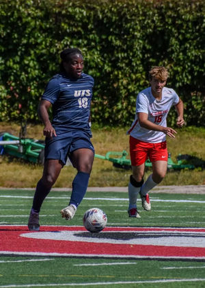 Nathan Oba-Okusanya playing soccer at away game in blue UIS uniform