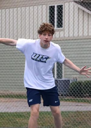 Kai Van-Roon playing tennis in white UIS uniform