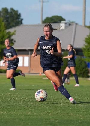 Mallory Herber playing soccer in blue UIS uniform