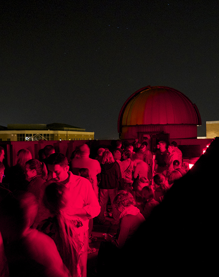 People gather for a Star Party on the roof of Brookens Library at night.