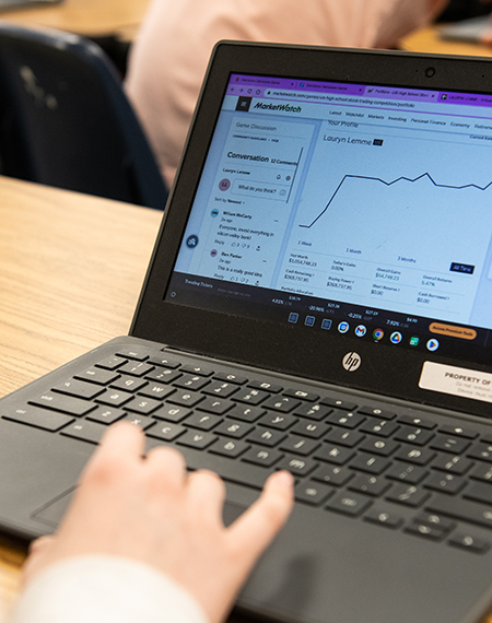 A hand on a laptop computer with the screen showing the MarketWatch platform.