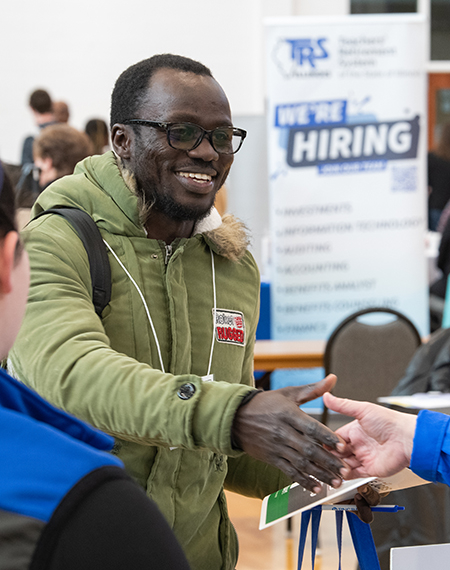 A student shakes hands with an employer at the 2024 UIS Career Connections Expo, networking for job and internship opportunities.