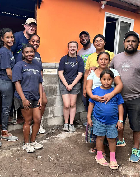 A group of UIS students and local residents stand in front of a newly built home during a service trip in Guatemala.