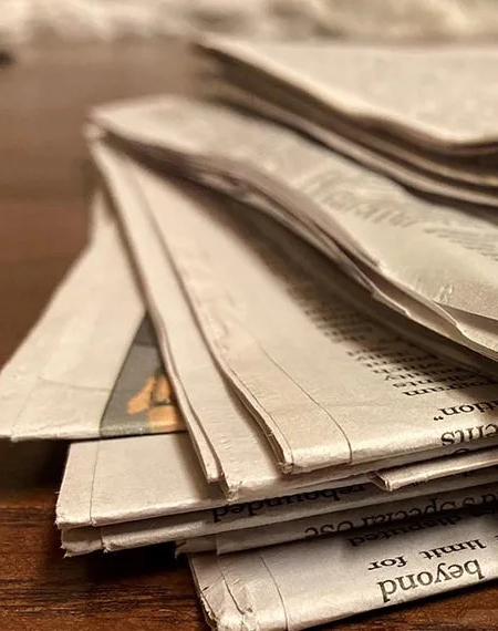 A stack of newspapers on a desk.