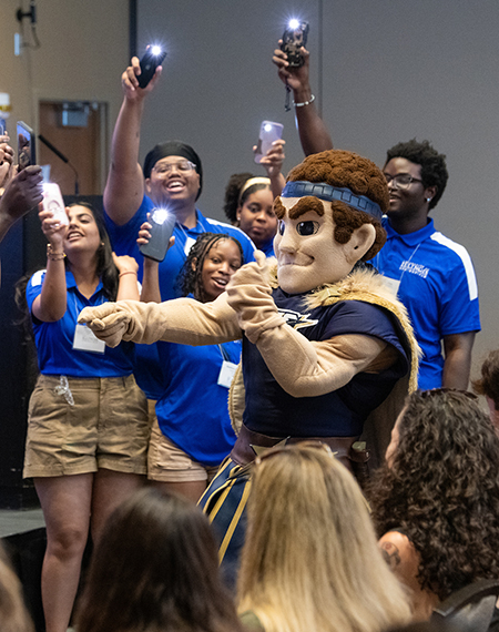 Orientation leaders dance around UIS mascot Orion at a First-Year Student Orientation event.