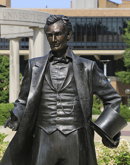 Statue of Abraham Lincoln with the UIS colonnade in the background.