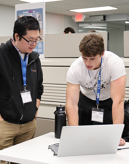 Two men collaborating at a laptop in an office setting.