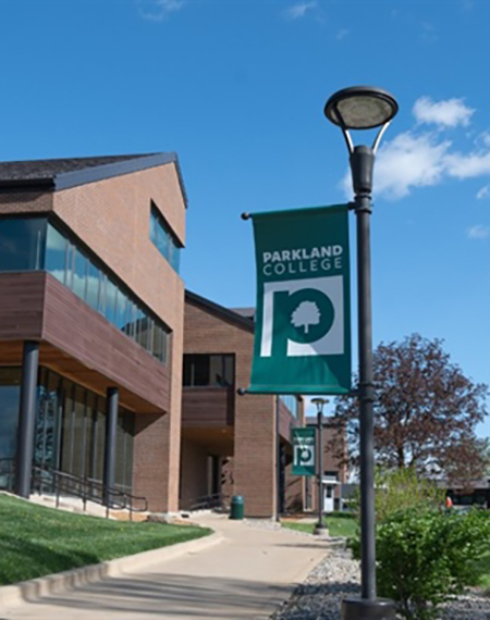 Parkland College banner on a lamppost, clear blue sky.