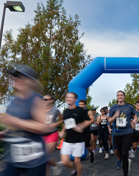 Runners passing a blue inflatable arch, blurred motion.