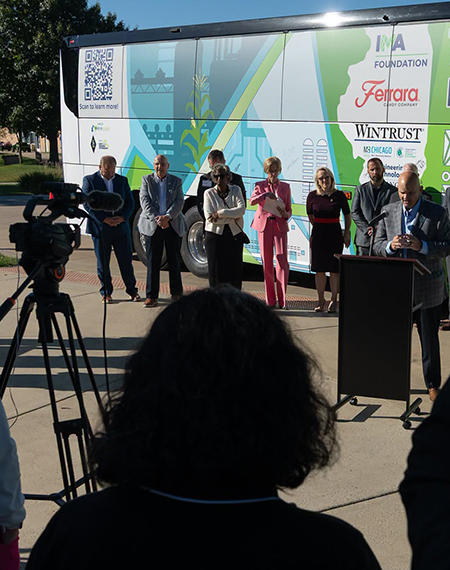 People standing in front of a brightly colored bus, with camera setup in foreground.