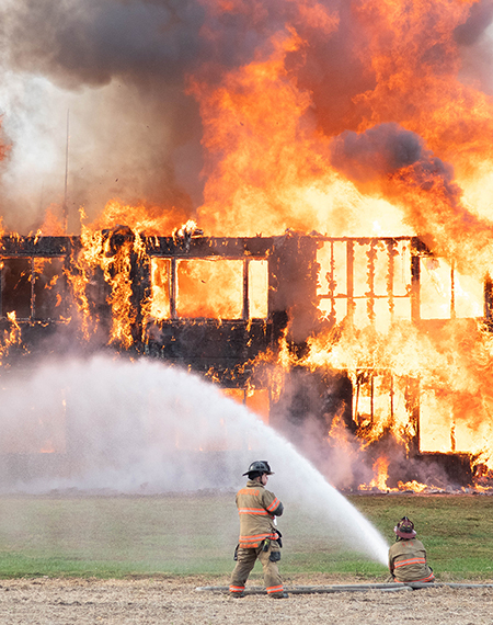 Firefighters extinguishing a large building fire with hoses.