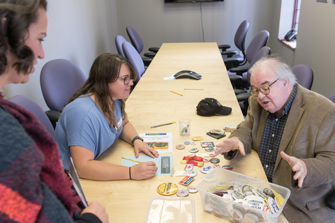 A student discusses historical buttons with a community member