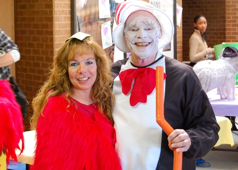 A woman standing next to a man dressed as Cat in the Hat.