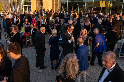 large group of people gather on a patio to talk in various groups