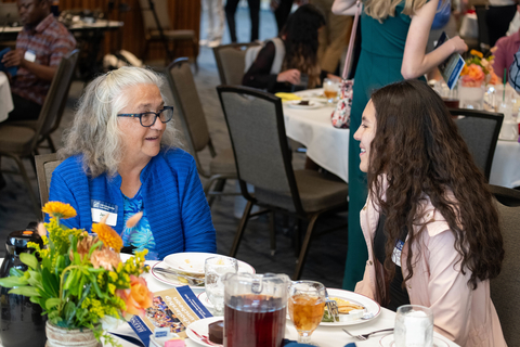 A woman and female student sitting at a table talking at the 2023 UIS Scholarship luncheon.