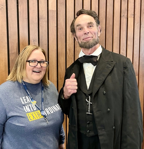 A woman standing next to a man dressed as Abraham Lincoln.