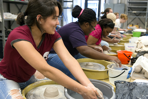 art students at potter's wheels making pottery