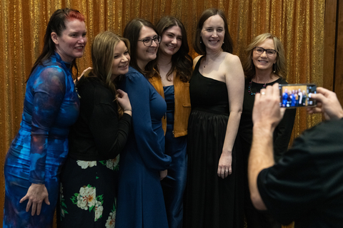 A group of women pose in a photo booth