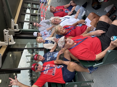 a group of people pose for a photo while attending a baseball game