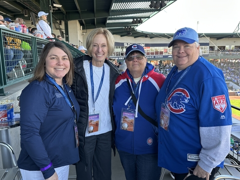 four people pose for a photo while attending a baseball game