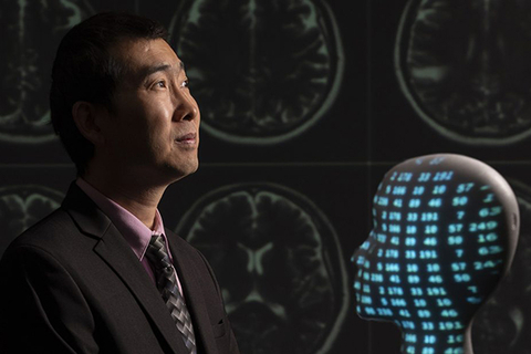 Faculty member in front of brain scan images and AI data projection